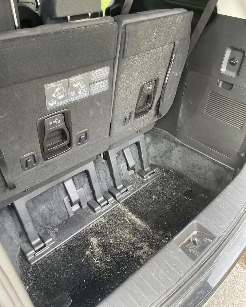 Same SUV cargo area before, covered in dust and pine needles